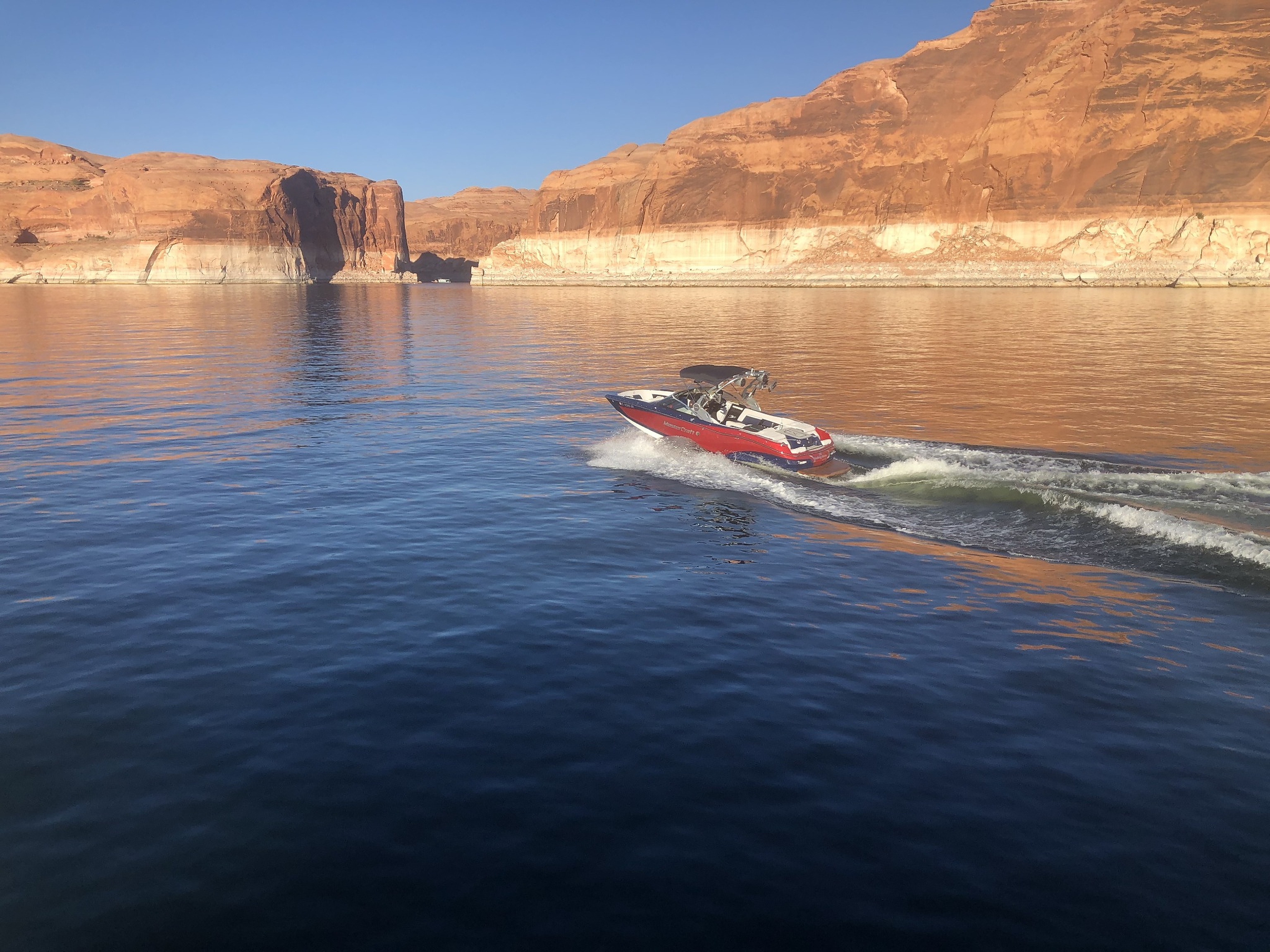 A boat cruising across a lake surrounded by sandstone cliffs
