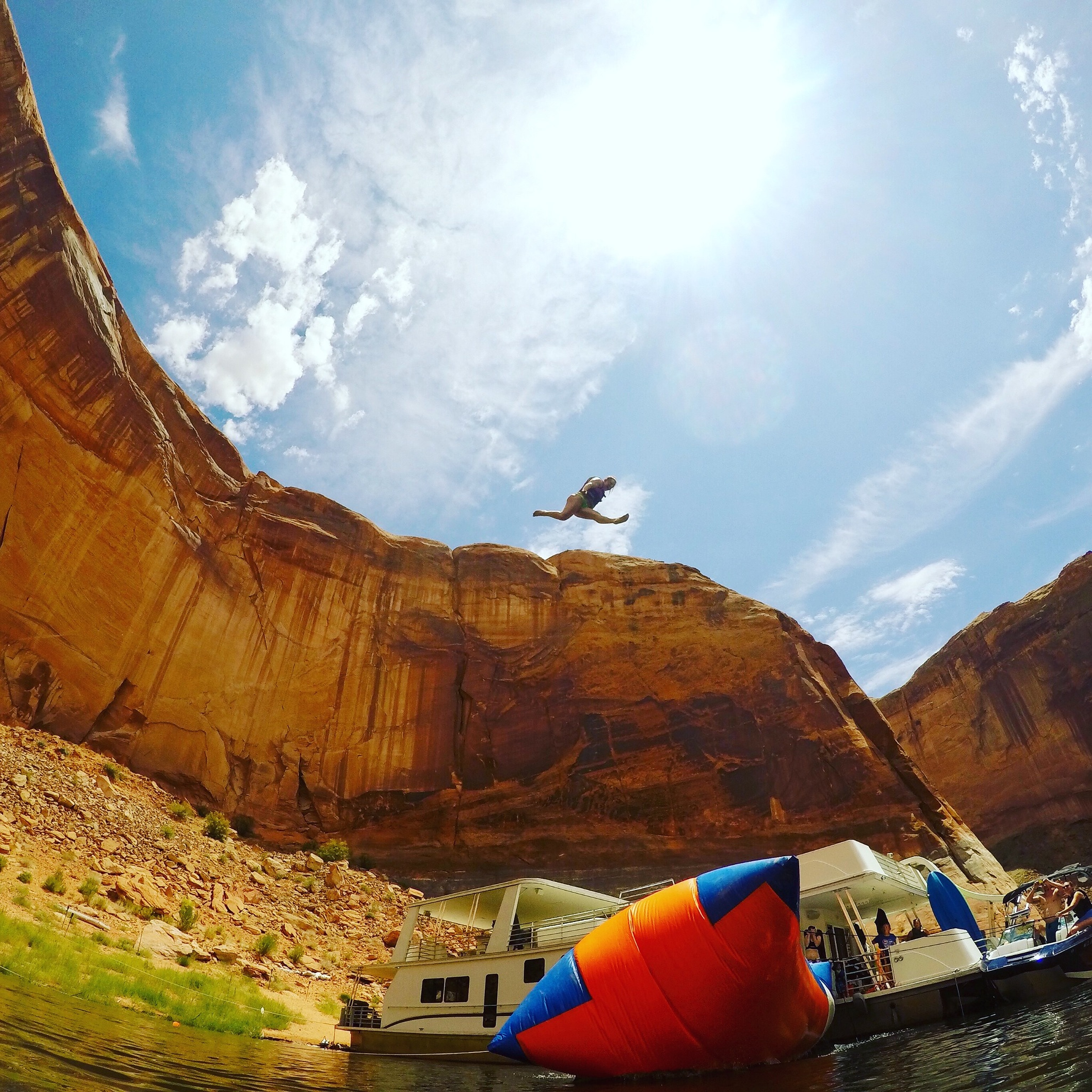 A lakeside leap beside sandstone cliffs and a houseboat