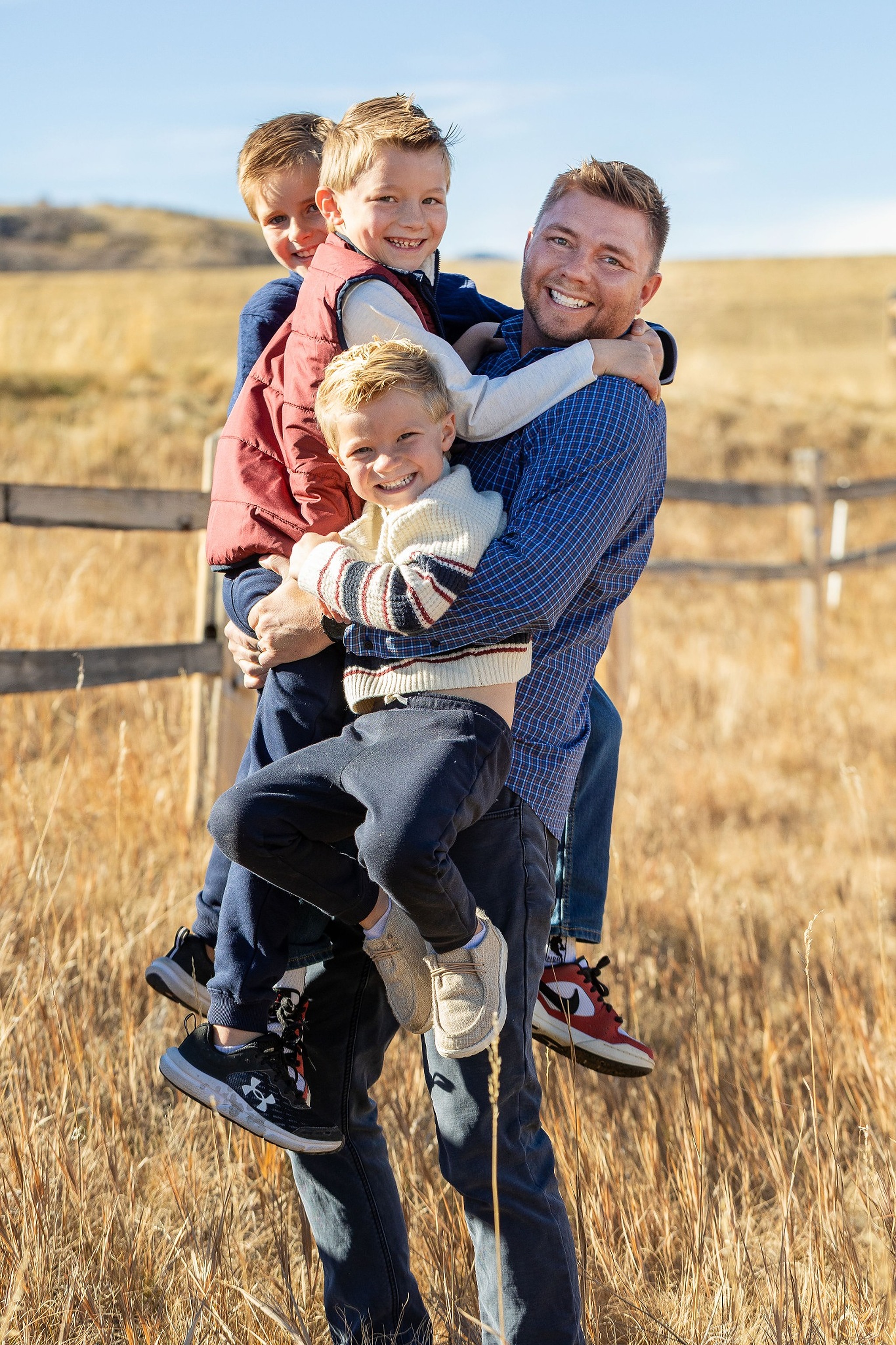 Dane holding his three boys outdoors